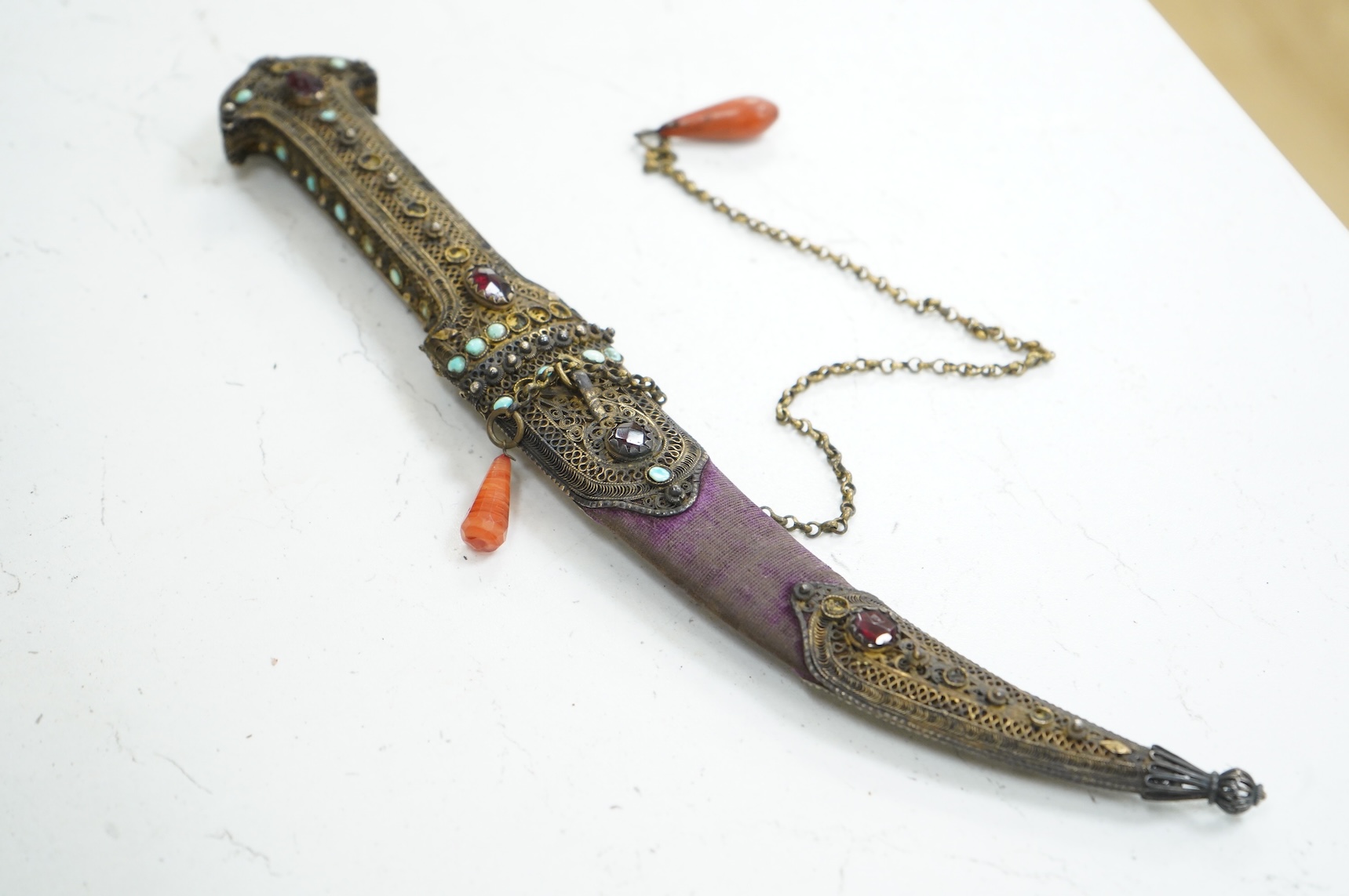 A Late 19th century Hungarian dagger, the hilt and sheath mounts made from filigree gilt silver wire applied with cabochon turquoise and red stones (some missing), blade 13.5cm